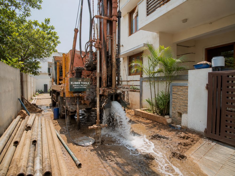 Residential borewell drilling rig outside a home